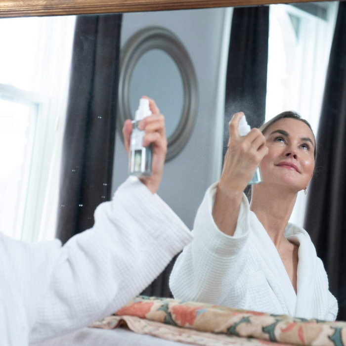 graydon moffat, founder of graydon skincare, wears a fuzzy robe and spritzes face food mineral mist on her face in the bathroom
